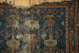 Upper corner of Vintage Malayer rug, deep blue and copper geometric pattern, tattered fringe.
