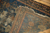 Detail of a vintage Malayer rug showing a quarter-sized hole and visible light foundation.