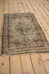 Worn Kerman rug with ivory, navy, cochineal floral arabesques and prominent exposed foundation.