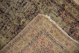 Worn pile of antique Kerman rug revealing hand-knotted foundation and tattered fringe.