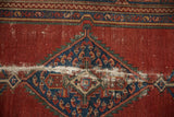 Vintage Malayer rug, diamond medallion in indigo blue and cherry red, with visible foundation wear.