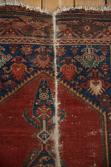 Vintage Malayer rug top edge with foundation wear, tattered fringe, cherry red, and indigo borders.