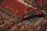 Textural pile of vintage Malayer rug, cherry red and indigo blue with visible wear.