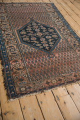 Antique Malayer rug with dusty blush boteh field, reciprocating wave border, and tattered fringe.