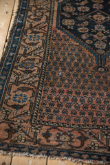 Antique Malayer rug: dusty blush boteh field, navy wave border, and visible side tatter.