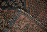Antique Malayer rug's folded corner reveals dusty blush boteh, navy vinery, wave motif, and aged fringe.