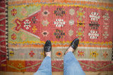 Overhead view of a vintage Turkish Kilim's flatweave texture and colorful geometric floral motifs.