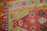 Hand-woven texture of a Turkish Kilim with a geometric vine border and colorful floral motifs.
