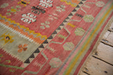 Faded cochineal red and saffron yellow geometric florals on a handwoven vintage Turkish kilim rug.