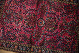 Vintage Lilihan rug detail, cherry red field with navy blue floral sprays and patterned border.
