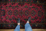Hand-knotted vintage Mehreban rug's raspberry red field with geometric vinery and blossoms.