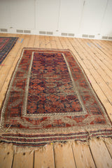 Antique Belouch runner end: worn hook and latch border, tattered fringe, exposed foundation.