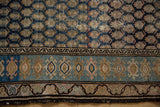 Vintage Hamadan rug border in dusty indigo, pale rose, and ivory, with visible tatter.