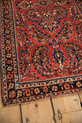 Angled detail of a vintage Sarouk rug's finely woven floral bouquets and navy border.