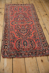 Vintage Sarouk runner shown at an angle, revealing its dense floral pattern on a brick red field.
