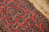 Close-up on the finely woven floral bouquets and navy blue main border of a vintage Sarouk rug.