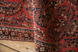 Folded view of a vintage German Sarouk rug highlighting its finely woven texture and floral bouquets.