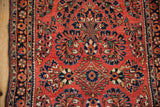 Close-up of the floral bouquets and detailed border on a vintage brick-red Sarouk rug.