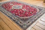 Intricate corner spandrel and floral border of a vintage Nain carpet in cherry red and navy blue.