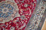 Perched birds and dragon motifs in the corner spandrel of a vintage red and blue Nain carpet.