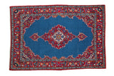 Vintage fine Kashan rug with a scalloped red medallion, deep blue field, and colorful floral blossom border.