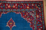 Corner detail of a fine Kashan rug's cherry red floral blossom main border.