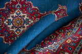 A fine vintage Kashan rug draped to show the deep blue field and intricate red floral designs.