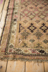 Close-up of vintage Caucasian rug's geometric border, tattered fringe, in camel, pink, and brown.