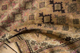 Folded vintage Caucasian rug pile, showcasing geometric guls in camel, pink, and brown.
