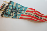 Red and beige stripes of the vintage felt flag with 'STATUE of LIBERTY' text.
