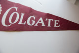 Close-up of vintage Colgate felt pennant: white lettering, burgundy fabric, visible tear and stains.