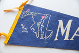 Close-up of vintage Maryland felt pennant, showing royal blue texture, yellow binding, and 'The Free State' text.