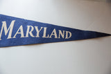 Vintage Maryland felt pennant displaying 'RYLAND' in textured off-white letters on blue.