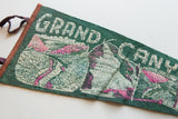 Green felt Grand Canyon pennant with white 'GRAND' text, pink canyon scene, and rust binding.
