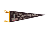 Dark brown vintage Empire State Building felt pennant with white graphic and yellow edge.