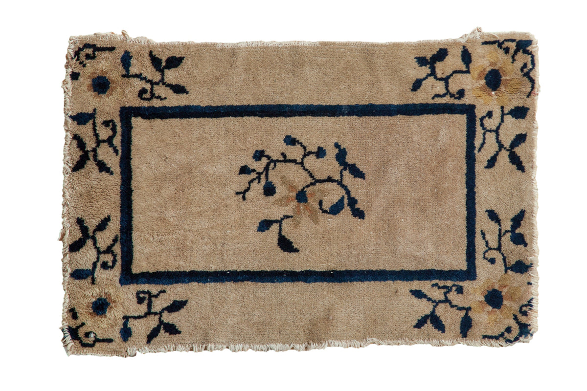 Antique Chinese Peking rug mat, central floral spray, dark blue border on beige.