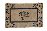 Antique Chinese Peking rug mat, central floral spray, dark blue border on beige.