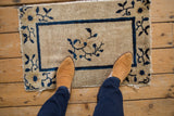 Antique Peking rug mat with cobalt blue floral spray, shown with feet.