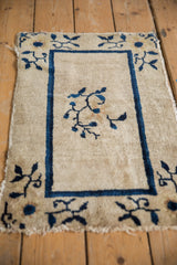 Antique Peking rug corner with cobalt blue border, floral motif, tattered edge.