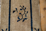 Antique Chinese Peking rug with beige pile, cobalt blue floral vine, and edge wear.