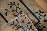 Antique Peking rug folded, showing blue floral motifs, fringe, and multicolor reverse.