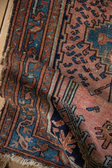 Vintage Mehreban rug corner: Worn fringe, time-softened cochineal red and sapphire blue motifs.