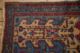 Corner of a hand-knotted Mehreban rug with stylized plant motifs in gold, blue, and red.