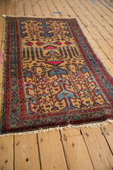 Angled view of a vintage Mehreban rug, showing the geometric pattern on a gold field with red and blue details.