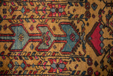 Stylized arrowed motif in sky blue and raspberry red on the hand-knotted golden wool pile.