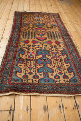 Angled view showing the repeating gold, blue, and red motifs of a Persian rug.