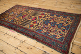 Angled perspective on a vintage Mehreban rug with a weeping willow design in gold, red, and blue.