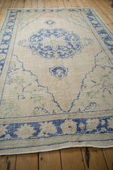 Distressed Oushak rug, textured book cover spandrel with beige and pale blue.