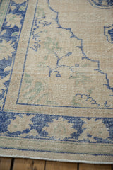 Distressed vintage Oushak rug pile, featuring worn beige, pale cobalt blue border, and seafoam green.