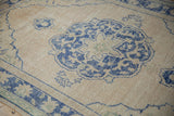 Distressed vintage Oushak pile with beige field and royal blue floral arabesques.